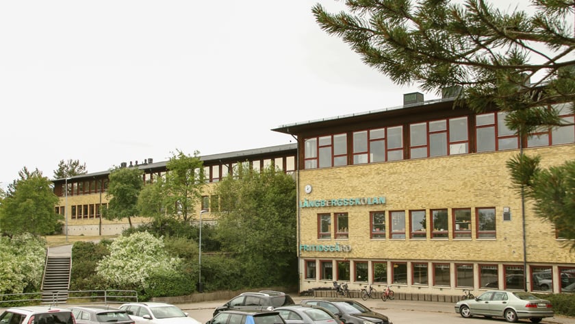 Byggnaden för Gruvans skola Långberg, gul tegelbyggnad, klocka upptill, bruna fönsterkarmar upp till